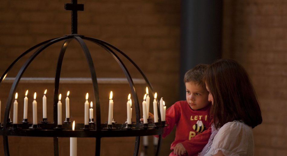 Mor og barn som tenner lys i kirke