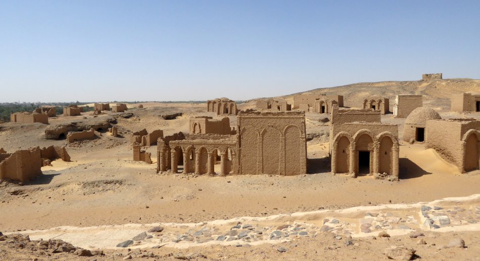 A photo of a desert landscape with ancient arched buildings.