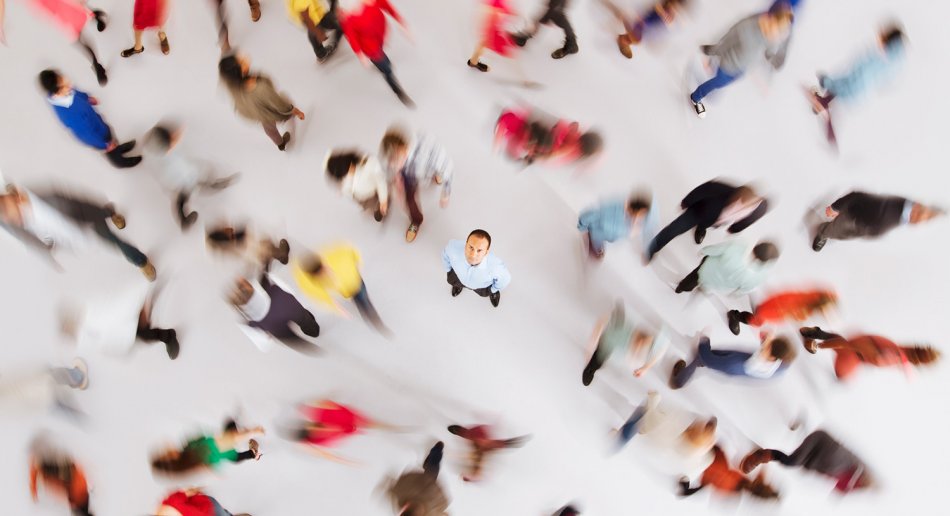 mann som ser opp mot kamera. Sirkel med personer ute av fokus som går rundt han.