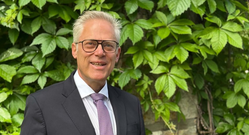 Mann med briller foran grønne blader