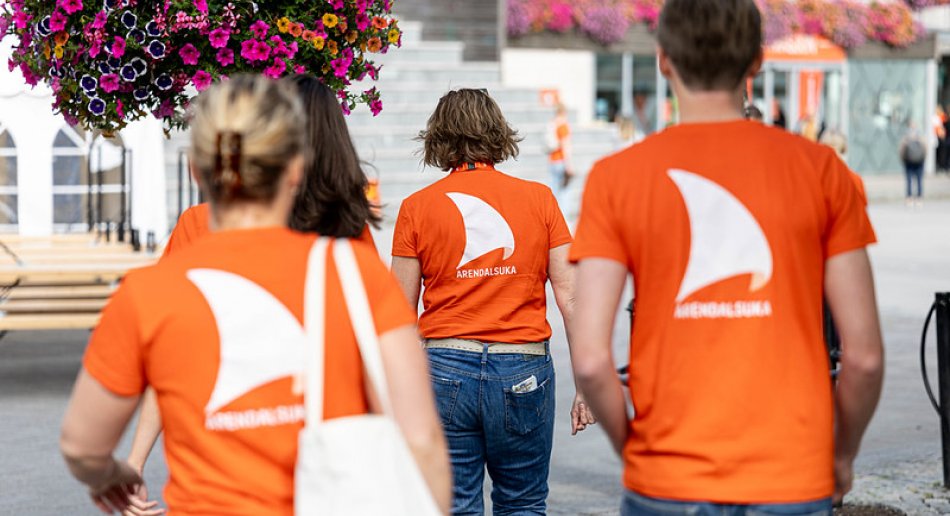Fire mennesker med t-skjorter fra Arendalsuka går bort fra oss.
