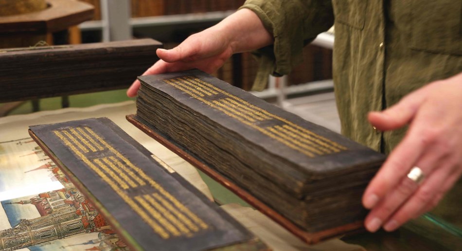 hender som blar i et gammelt sanskrit-manuskript