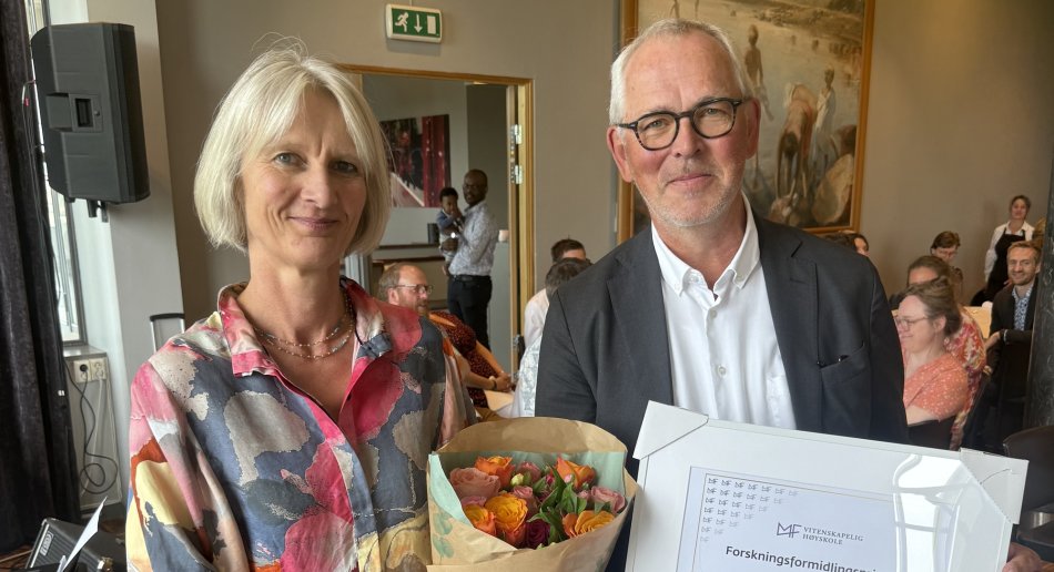 Professor Claudia Lenz holder en blomsterbukett. Rektor Vidar Haanes holder diplomet for forskningsformidlingsprisen.