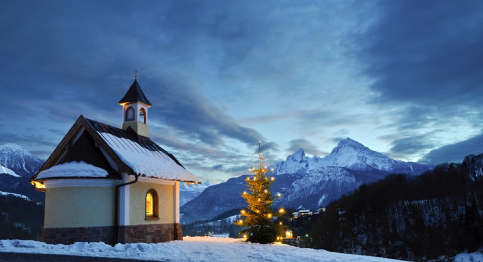 Kirke i snøkledde omgivelser. Juletre utenfor.