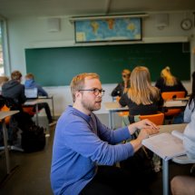 Mannlig lærer i samtale med gutt i klasserommet.