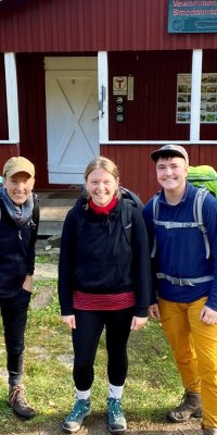 Gruppe med fem glade studenter utenfor en norsk hytte